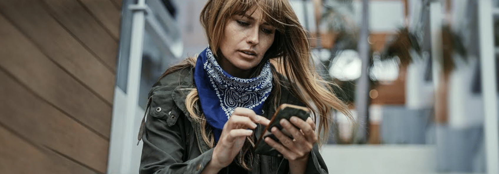imagem de uma mulher usando seu celular em local aberto