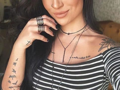 mulher com aneis, colares e tatuagens no braço