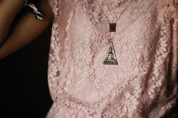 Pessoa com roupa rosa e colar de buda.