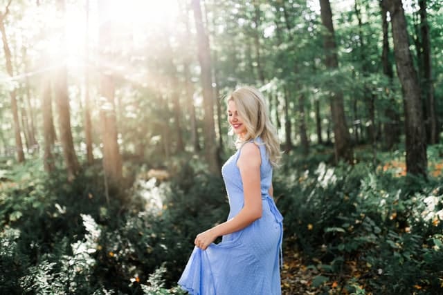 Mulher usa vestido azul em floresta