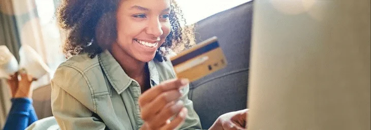 mulher deitada em sofá segurando um cartão de crédito