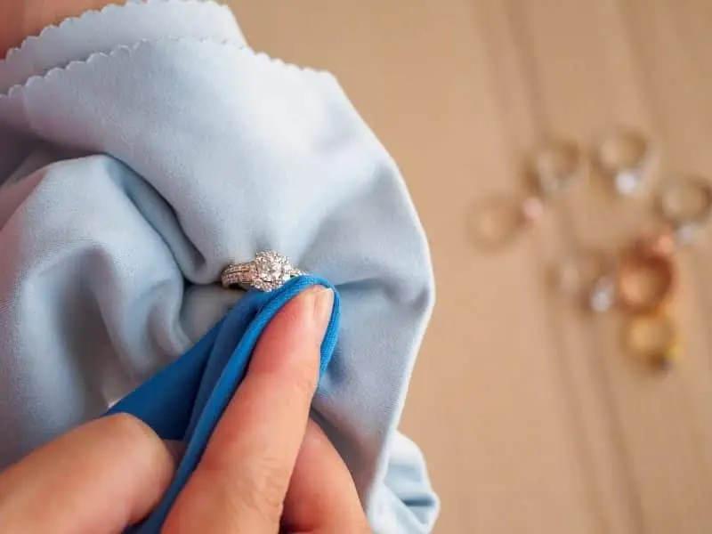 mão limpando um anel com flanela, simbolizando uma forma de limpar semijoias
